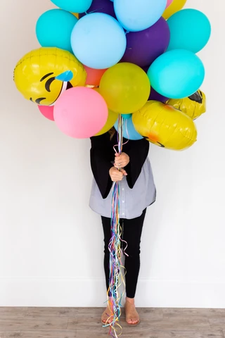 Woman standing behind group of balloons she's holding